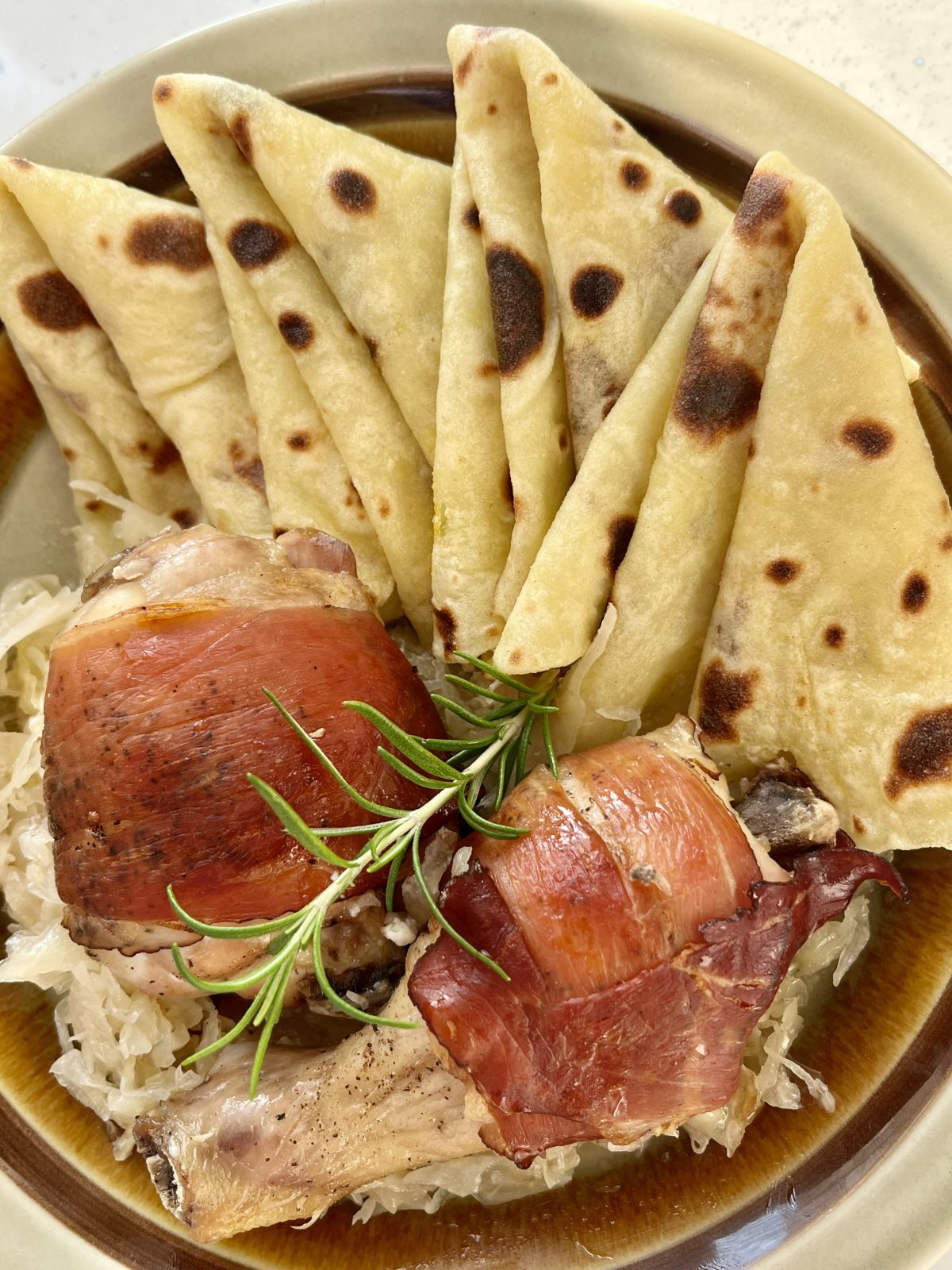 Pečené stehná v prosciutte na kyslej kapuste so zemiakovou lokšou